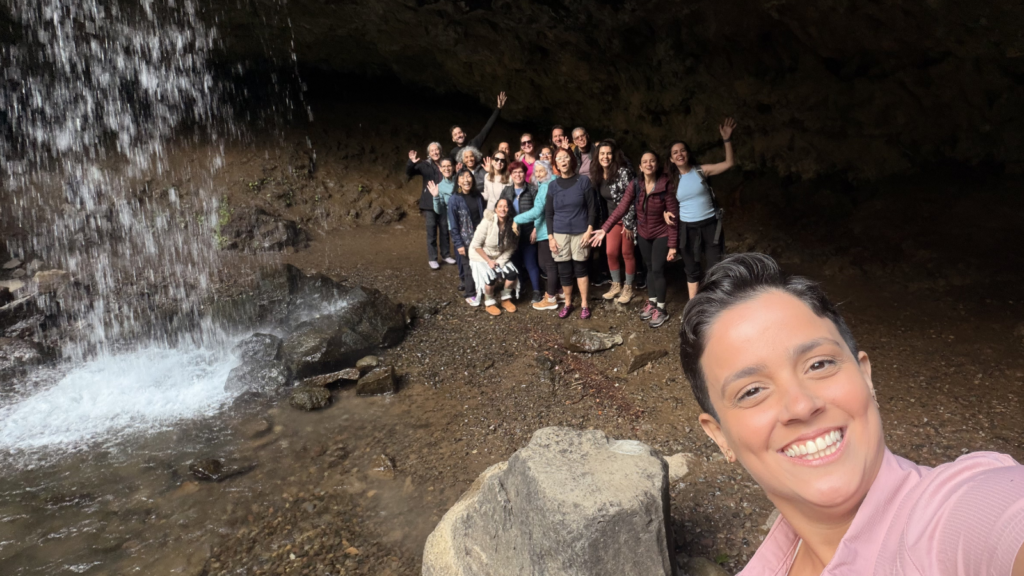 Rayani selfie with spiritual retreat group gathered in front of a waterfall