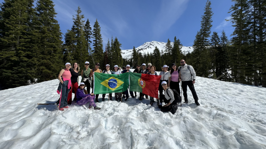 Retreat participants posing with Brazilian flag in snow near Mount Shasta