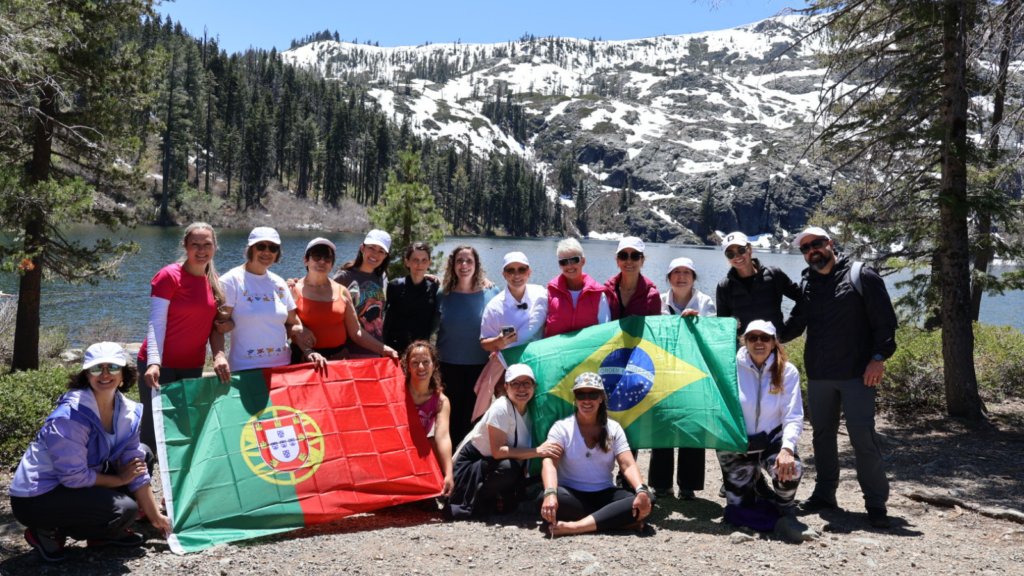 Retreat participants holding Portugal and Brazil flags in a snowy mountain forest
