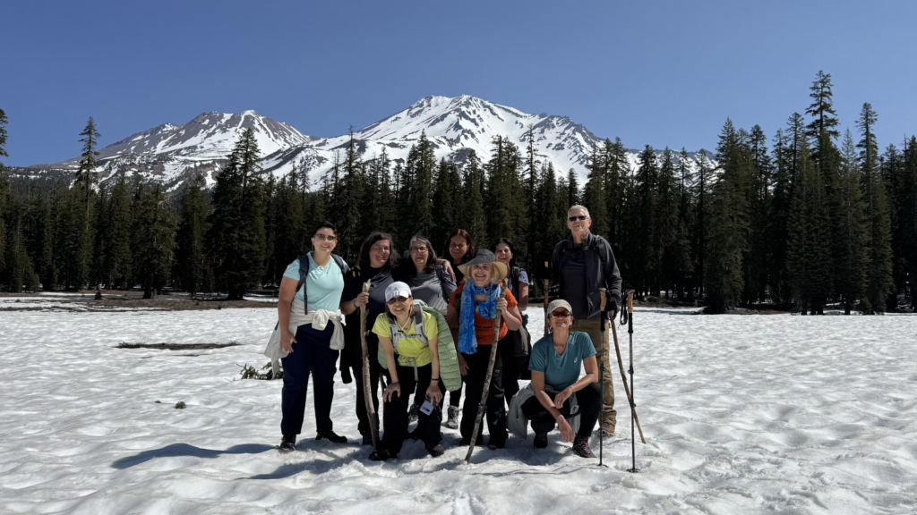Spiritual retreat group posing together on snow with mountain peak background